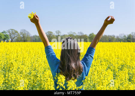 Junge Frau bringt Glück mit den Armen oben in gelb Raps Feld Stockfoto