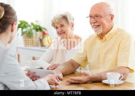 Lächelnd älterer Mann und Frau im Gespräch mit einem Finanzberater über ein Darlehen Stockfoto