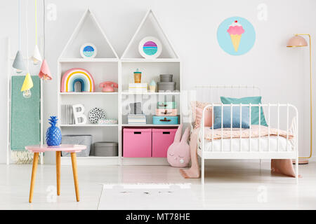Vorderansicht des ein Kinderzimmer Einrichtung mit einem Tisch, Regale mit Kästen und Rainbow, Einzelbett und Eis Poster an der Wand Stockfoto