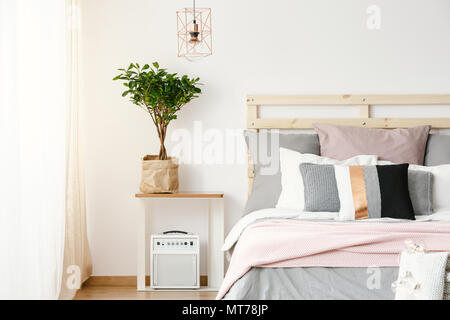 Auf dem Tisch neben dem Bett mit dekorativen Kissen in der modernen Schlafzimmer Innenraum. Real Photo Stockfoto