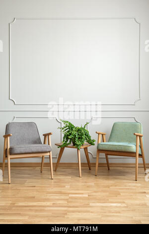 Anlage auf hölzernen Tisch zwischen Sesseln in minimalen Wohnzimmer Interieur mit kopieren. Real Photo Stockfoto