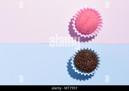 Brasilianische Spezialitäten: Brigadeiro und Bicho de Pe. Kindergeburtstag. Flache Ausführung von candy Kugel auf farbigen Hintergrund. Stockfoto