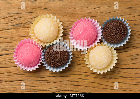 Brasilianische Spezialitäten: Brigadeiro, Beijinho und Bicho de Pe. Kindergeburtstag. Overhead von candy Ball auf rustikalen Holztisch. Stockfoto