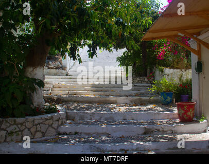 Steinerne Treppe in Richtung des Lichtes, mit Bäumen und Blumen in Töpfe in Fiskardo auf der griechischen Insel Kefalonia Stockfoto