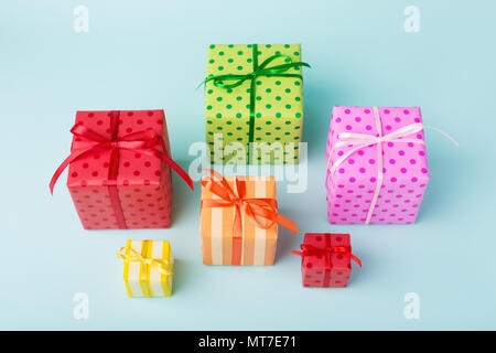 Urlaub bunte Geschenkboxen in bunten Papier und Bögen auf blauem Hintergrund gewickelt. Geburtstag, Weihnachten Stimmung und Verkauf Konzept. Stockfoto