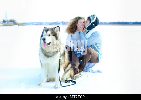 Nahaufnahme der Fang von Husky mit dem küssen paar im Winter Hintergrund. Konzept der Haustiere und Wandern mit Hunden. Stockfoto