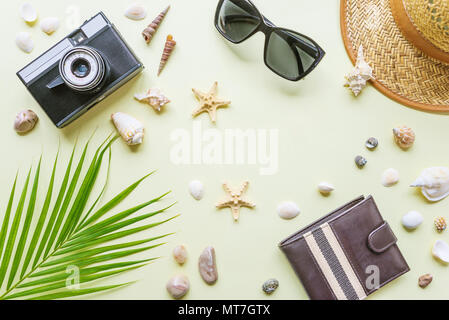 Traveler Zubehör: grünen, tropischen Palm Leaf, Foto Kamera, Muscheln und Sonnenbrillen sind auf gelbem Hintergrund mit copy-Platz. Ansicht von oben reisen oder Va Stockfoto