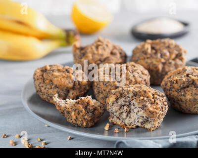 - Nahaufnahme Blick auf gesunde Glutenfreie homemmade Banana Muffins mit Buchweizen Mehl. Vegane Muffins mit Mohn auf der grauen Platte über grau Holztisch Stockfoto