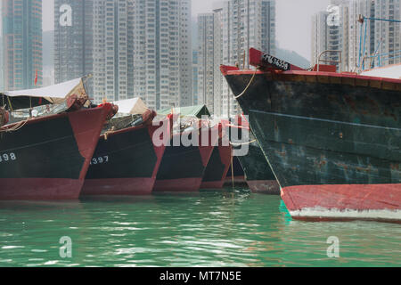 Der kommerzielle Fischfang Boote aufgereiht auf den Hafen von Hong Kong mit Ferienwohnungen im Hintergrund Stockfoto