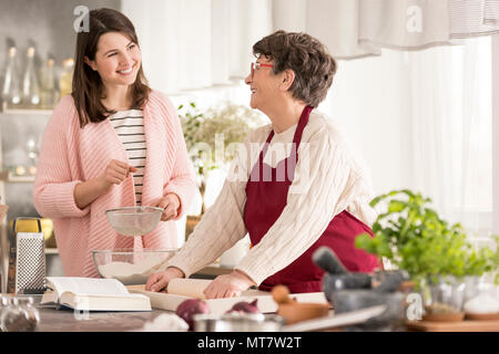 Glückliche Enkelin Oma helfen in eine moderne Küche Stockfoto