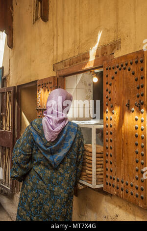 Marokkanische Dame mit Schal kaufen Brot in der Medina von Rabat Stockfoto
