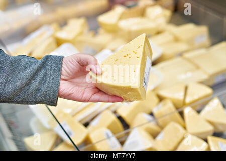 Hand des Käufers mit einem Stück Käse im Store. Stockfoto