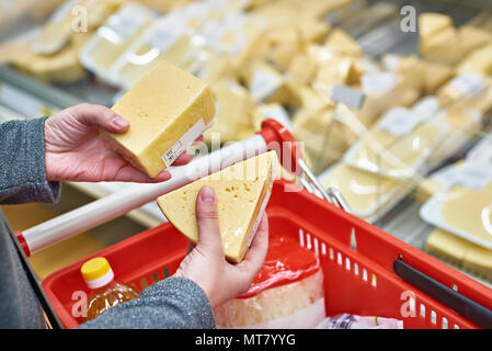 Die Hände des Käufers mit einem Stück Käse im Store. Stockfoto