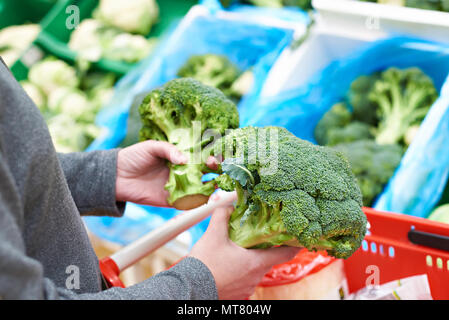 Frau kauft Brokkoli in einem Lebensmittelgeschäft Stockfoto