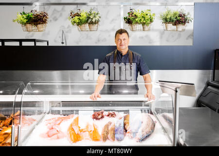 Männliche Verkäufer mit Meeresfrüchte in Fish shop Kühlschrank Stockfoto