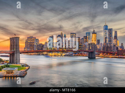 New York, New York, USA Skyline von Manhattan über den East River und die Brooklyn Bridge nach Sonnenuntergang.