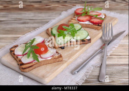 Sandwiches mit Frischkäse, Rettich, frische Gurke, Erdbeeren und Rucola. Stockfoto