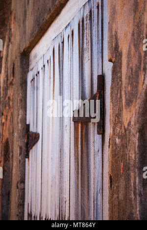 Eine alte und verwitterte weiße Tür mit rostigen Scharniere. Stockfoto
