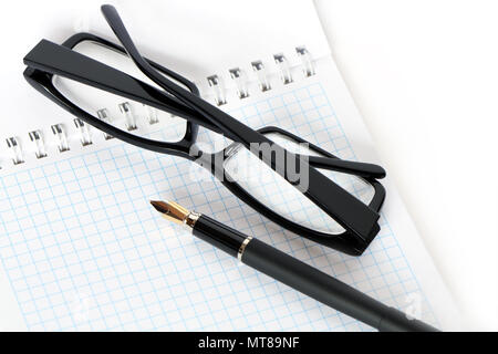 Nahaufnahme der Füllhalter und schwarze Brillen liegen auf offene Spirale Notebook Stockfoto