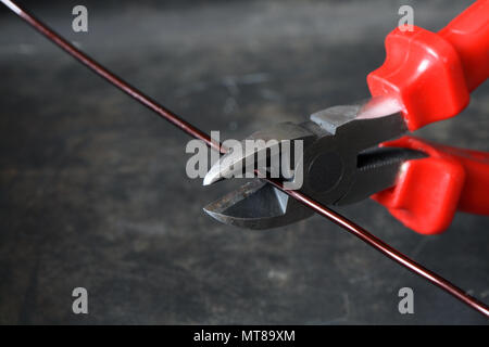 Nahaufnahme des Drahtschneider und Kabel auf dunklem Metall Hintergrund Stockfoto