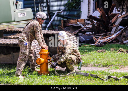 Die 1192nd Engineer Company ist eine Einheit der Ohio National Guard, die Ingenieurmissionen zugewiesen hat. Am 14. Juli 2017 verbinden Soldaten in Youngstown (Ohio) eine Wasserlinie mit einem Hydranten, während sie ein verurteiltes Haus im Rahmen des South Side Feught Removal and Greening Projekts im Rahmen des Civil-Military innovative Readiness Training Program des Verteidigungsministeriums abreißen. Das Archivbild zeichnet die Unterstützung der städtischen Abbrucharbeiten auf. Stockfoto