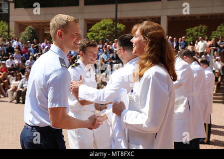 Air Force 2 Leutnant Robert Pahissa (links) gratuliert von pensionierten Air Force Col (Dr.) Jessica Servey (rechts), als sie sich bereit, ihn mit seiner traditionellen medizinischen Schule weißen Mantel während einer Zeremonie zum 11. Mai 2018 zu präsentieren, an der Uniformed Services Universität der Gesundheitswissenschaften (USU), Bethesda, Md. Die Zeremonie wird jährlich für Studienanfänger an der USU F. Edward Hebert Schule von Medizin gehalten -- 'America's Medical School' - den Übergang in die klinische Praxis und die Versorgung der Patienten zu ehren. Servey ist Prodekan der Fakultät für Entwicklung an der Hebert Schule von Medizin. Stockfoto