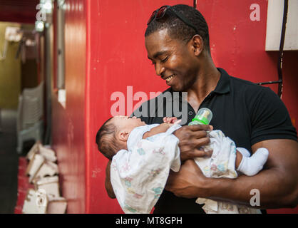 Us Marine Master Sgt. Leroy Forbes, eine Konstruktion Leiter mit 9 Engineering Support Battalion, 3. Marine Logistik Gruppe, und ein Eingeborener von Hartford, Conn, hält Baby Devin während einer Community Relations bei den sanften Händen Kinderbetreuung in Quezon City, Philippinen, 13. Mai 2018, als Teil der Übung Balikatan 2018. Philippinische, US-amerikanischen, japanischen und australischen Service Mitglieder verbrachten Muttertag Freiwilligenarbeit in der Mitte als Teil einer Community Relations Aufwand in den Philippinen. Sanfte Hände ist ein Kinder- und Jugendhilfe Agentur bedeutet, auf den vorderen Linien der Rettungs- und rehabilitati zu sein Stockfoto