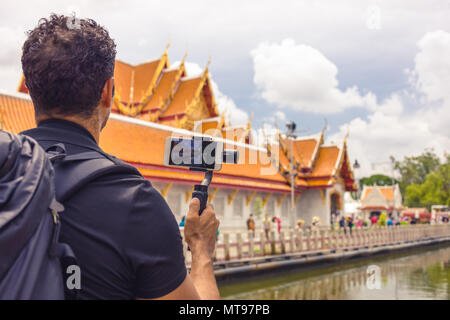 Mann backpacher Wer hält Mobiltelefon auf Gimbal Besuch in Asien an einem sonnigen Tag, Solo Reise, Urlaub und Ferien. Stockfoto