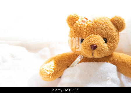 Teddybär lyiing krank im Krankenhaus Bett mit mit Thermometer und Gips. Gesundheitswesen und Medizinische Konzept. Stockfoto