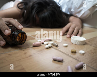 Frau auf dem Boden liegen nach einer Überdosis Pillen zu Hause. Überdosierung und Selbstmord Konzept. Stockfoto