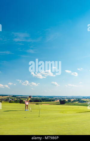 Entschlossene junge Frau Üben Golf auf dem Gras in der Ausbildung Bereich Stockfoto