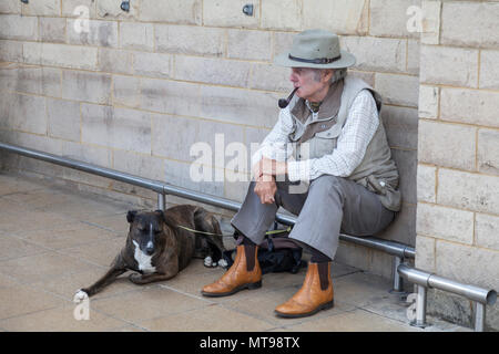 Ein älterer Mann, mit einem Rohr in den Mund, setzte sich außerhalb eines Shop mit seinen alten Hund an seiner Seite am Barnard Castle, England, Großbritannien Stockfoto