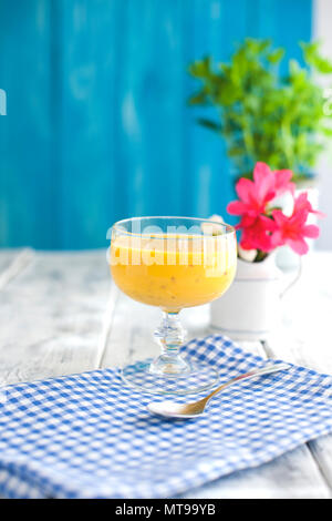 Smoothies von gelben Früchten, blau serviette und Holz- Hintergrund. Rosa Blüten. Für text Stockfoto