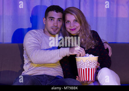 Junges Paar beobachten, Thriller Film im dunklen Zimmer mit Popcorn auf dem Sofa voll Aufmerksamkeit Stockfoto