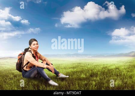 Hübsche asiatische tourist Frau mit Rucksack entspannende und sitzen auf den grünen Bereich Stockfoto