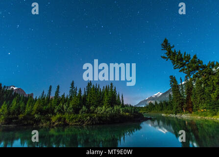 Bildunterschrift des Nordens: Sternenhimmel in der Bow River Valley im Banff National Park. Berge und Bäume in den blauen Gewässern wider. Campingplatz, Zelt. Stockfoto