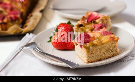 Ein Stück von Erdbeeren und Rhabarber Torte. Wide Screen Getreide der hausgemachten Licht glutenfrei Sommer Dessert serviert auf nette Platte. Stockfoto