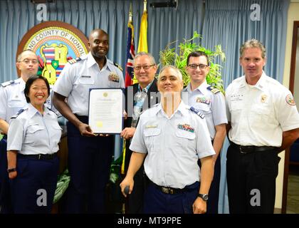 Cmdr. Ulysses Mullins, stellvertretender Kommandant, Coast Guard Sektor Honolulu (Mitte links), Roy K. Amemiya, Jr., Geschäftsführer, Stadt Honolulu, (Mitte rechts), Lt.Cmdr. Jon-Paul Del Gaudio, Direktor der Hilfs-, Coast Guard 14. Bezirk (Zweiter von rechts), Kevin Allen, Chef der, Ocean Safety und Rettungsschwimmer Services (rechts), und die Mitglieder der Hawaii - gegründete Coast Guard Auxiliary erhält einen Nationalen sicheren Bootfahren Woche Verkündigung vom Bürgermeister von Honolulu's Büros am 18. Mai 2018. In dieses Jahr fällt der 60. Jahrestag des Nationalen sicheren Bootfahren Woche. (U.S. Coast Guard Foto von Chief Petty Stockfoto