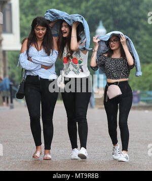 Menschen, die ihre Jacken zu Schutz von einem Regendusche im Alexandra Palace, London. Stockfoto