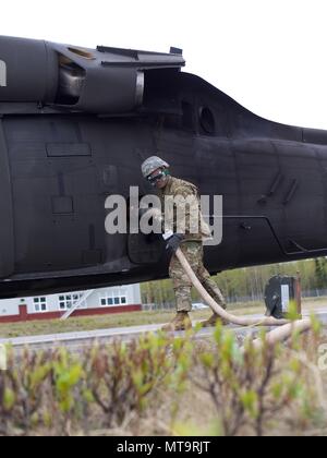 Alaska Army National Guard Pvt. Marvin Caparas, die Petroleumversorgung Spezialist Soldat mit E Unternehmen, 1.BATAILLON, 207 Aviation Regiment, tankt ein 1-207 th Aviation UH-60 Black Hawk Hubschrauber während vorwärts Bereich Rüstung und tanken Point Operations 19. Mai 2018, am Bryant Army Airfield, Joint Base Elmendorf-Richardson, Alaska. Die FAARP unterstützt die schnelle Auftanken von 1-207 th Aviation UH-60 s Während der wildfire Schulung. (U.S. Army National Guard Foto von Sgt. David Bedard / freigegeben) Stockfoto