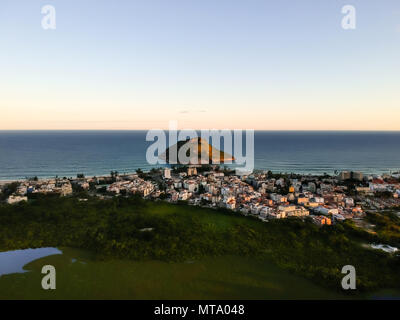 Antenne Landschaft Foto von Recreio dos Bandeirantes Strand bei Sonnenuntergang, mit Blick auf Chico Mendes Park und dem Pontal Stein gebadet durch orange Sonnenlicht Stockfoto