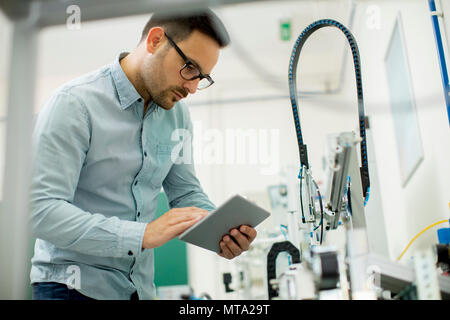 Portrait von gutaussehenden jungen Mann in der elektronischen Werkstatt mit digitalen Tablet Stockfoto