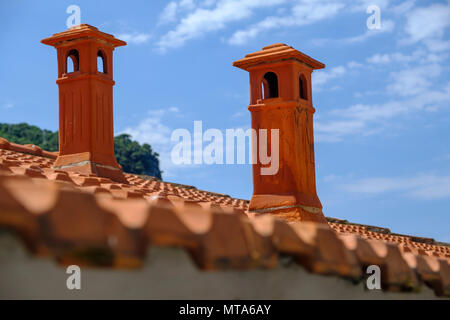 Schöne rote terracotta Schornsteine auf eine geflieste Dachterrasse in Portovenere Italien gegen den blauen Himmel Stockfoto