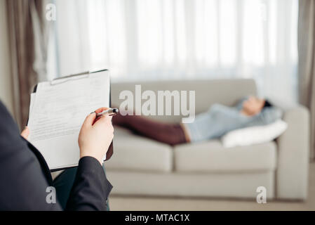 Weibliche Patient liegt auf Sofa bei psychotherapeut Rezeption. Ärztin schreibt Notizen in Notepad, professionelle Psychologie Unterstützung Stockfoto