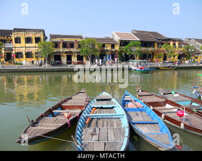 HOI AN, VIETNAM - 19. MÄRZ 2018: Schönen Tag in Hoi An Altstadt mit Blick auf die traditionellen Boote, gelbe Häuser am Ufer des Flusses, und die Touristen Stockfoto