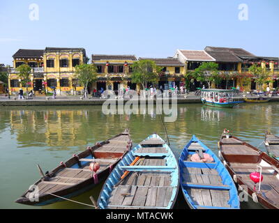 HOI AN, VIETNAM - 19. MÄRZ 2018: Schönen Tag in Hoi An Altstadt mit Blick auf die traditionellen Boote, gelbe Häuser am Ufer des Flusses, und die Touristen Stockfoto