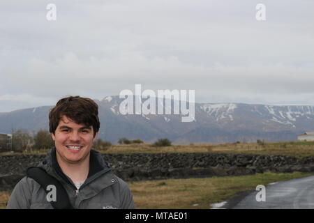 Touristische im Alter zwischen 20 und 25 stellt sich vor einer bergigen Region in Reykjavik Island Stockfoto