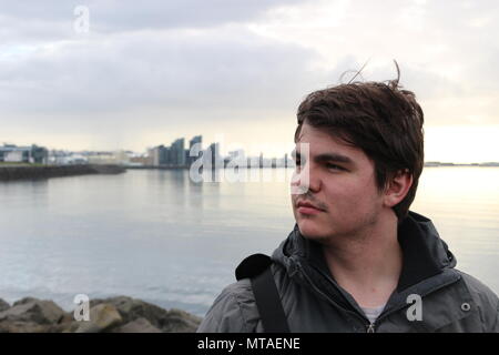 Männliche touristische posiert vor der Waterfront in Reykjavik, Island. Island hat sich zu einem beliebten Reiseziel für jüngere Reisende geworden. Stockfoto
