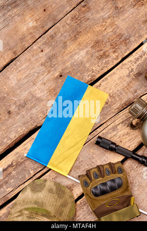 Ausrüstung und Essentials der ukrainischen Soldaten. Flach, Ansicht von oben. Schreibtisch aus Holz Tisch mit Copyspace. Stockfoto