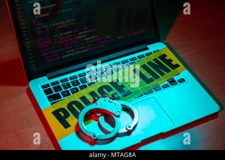Ein paar Handschellen und Polizei Kassetten sich auf einem Laptop Tastatur. Technologie/Internetkriminalität Konzept. Stockfoto
